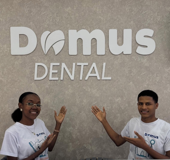 Dois membros da equipa Domus Dental junto à sinalética da clínica